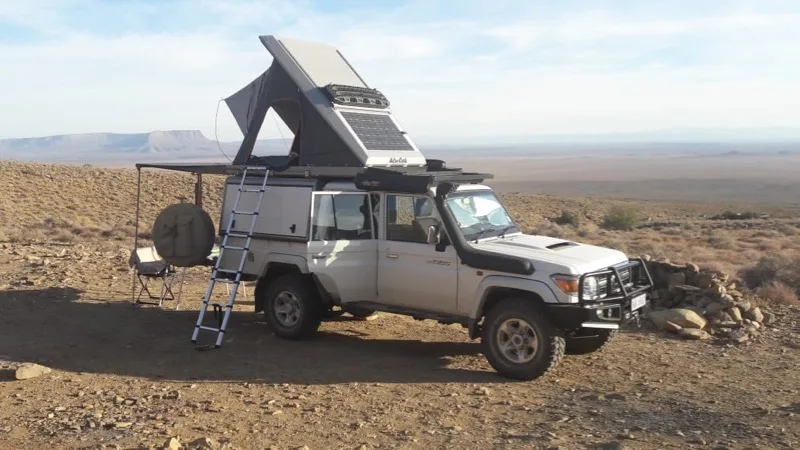 Land Cruiser 79 single cab with a pop-up roof tent, solar panel and awning set up at camp