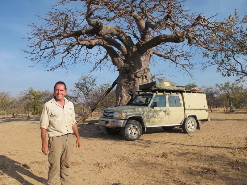 Paul Marsh beside a Land Cruiser 79 double cab under a baobab