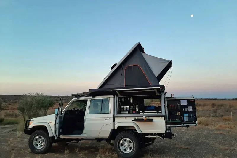 Land Cruiser pick-up with a pop-up camper at dusk