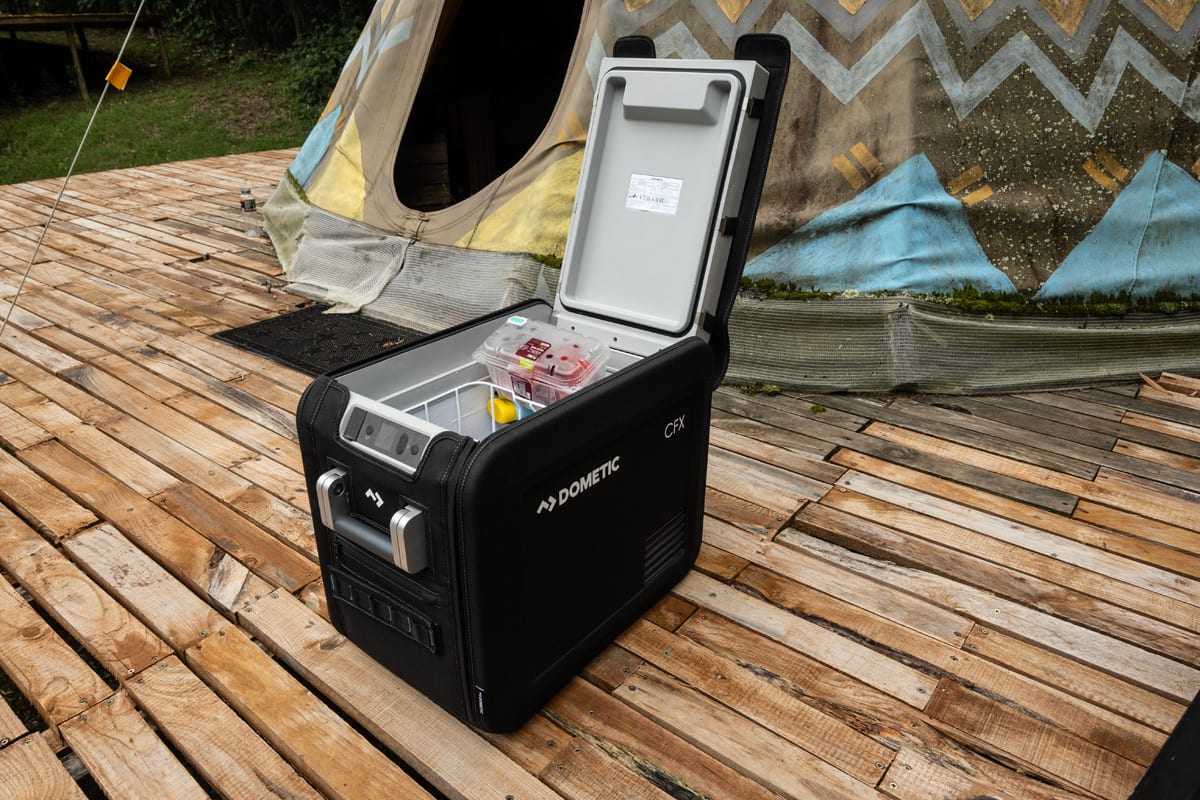 A Dometic compressor fridge, lid open, on a wooden campsite deck in Hogsback