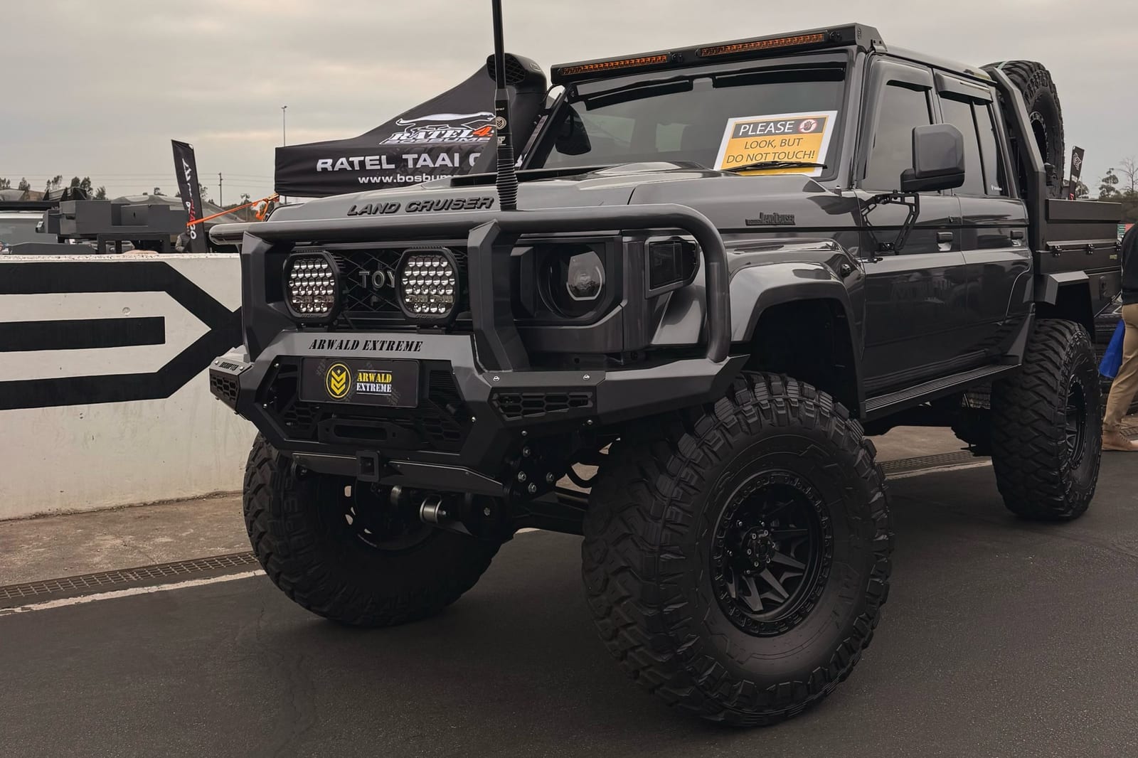 A heavily lifted grey new-shape Toyota Land Cruiser 79 double cab on very large tyres at an outdoor 4x4 show in Gauteng