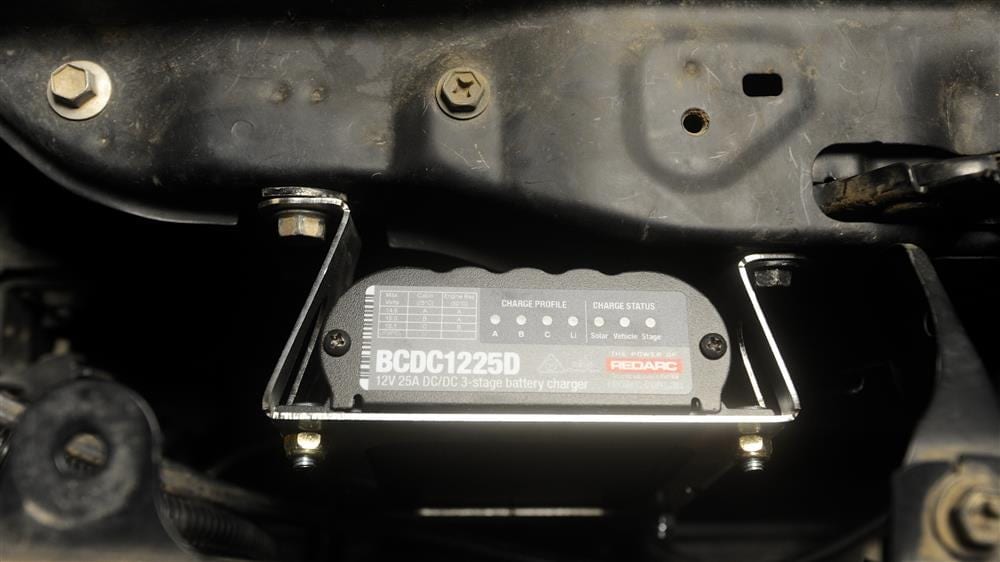 A 25 amp DC-DC battery charger bolted onto its bracket inside a vehicle