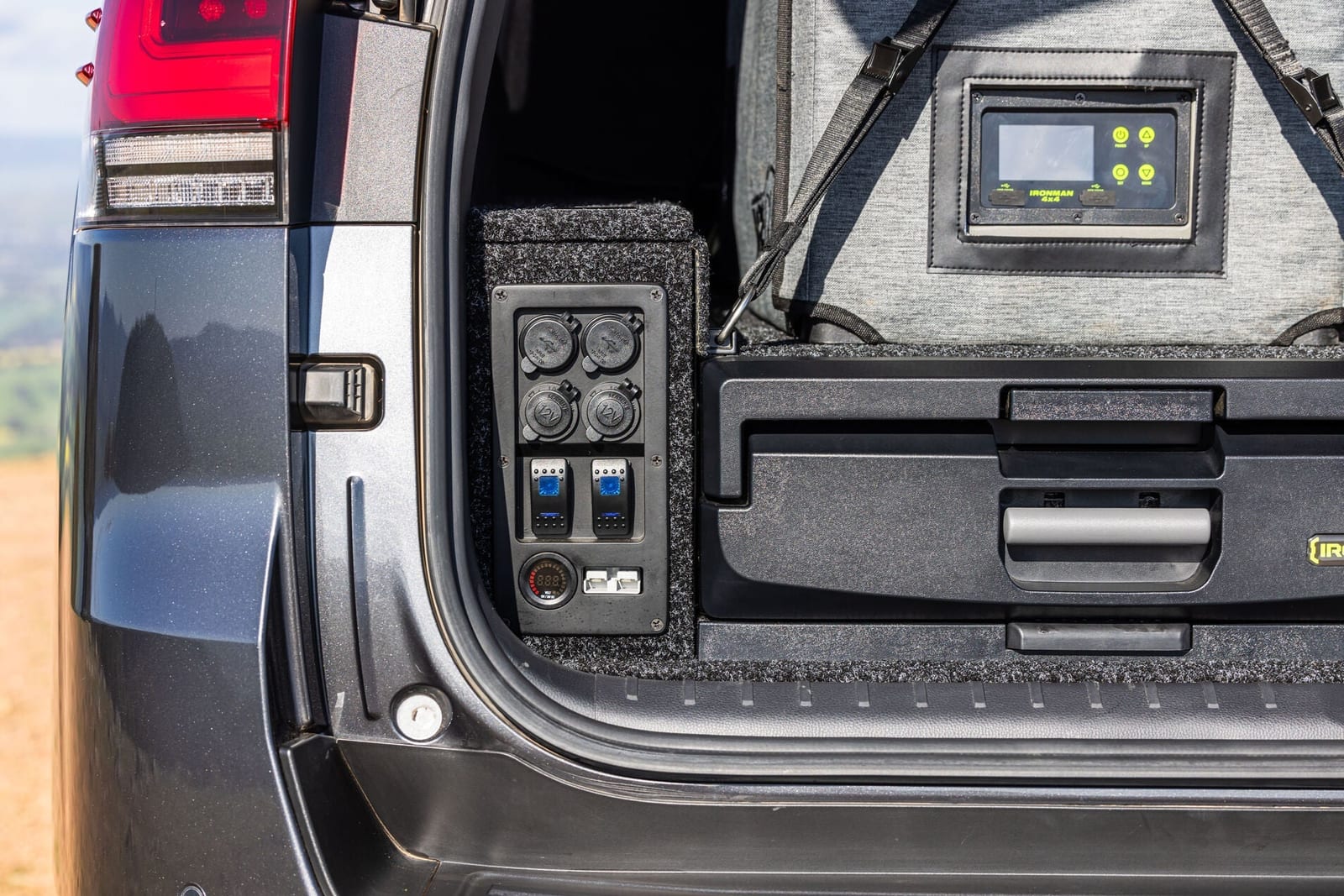 The load bay of a Land Cruiser 300 with a drawer system, a fridge on top and a built-in panel of 12V sockets and switches