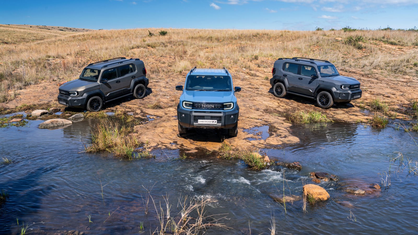 Three new Land Cruiser FJs parked in a stream on open veld.