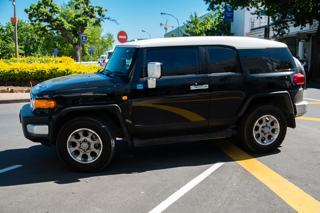 A black old-shape Toyota FJ Cruiser with a white roof parked in a Stellenbosch street.