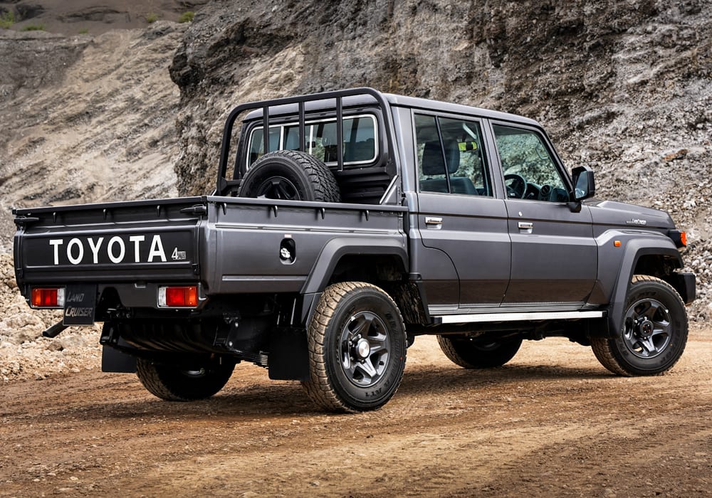 A dark grey new-shape Land Cruiser 79 double cab from the rear, parked on a gravel quarry road