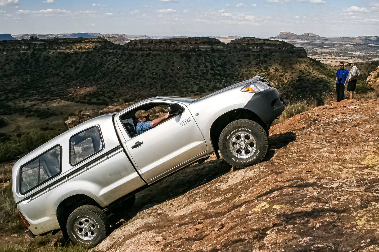 A silver Toyota Hilux single cab with a canopy climbing a rock slab in the Free State.