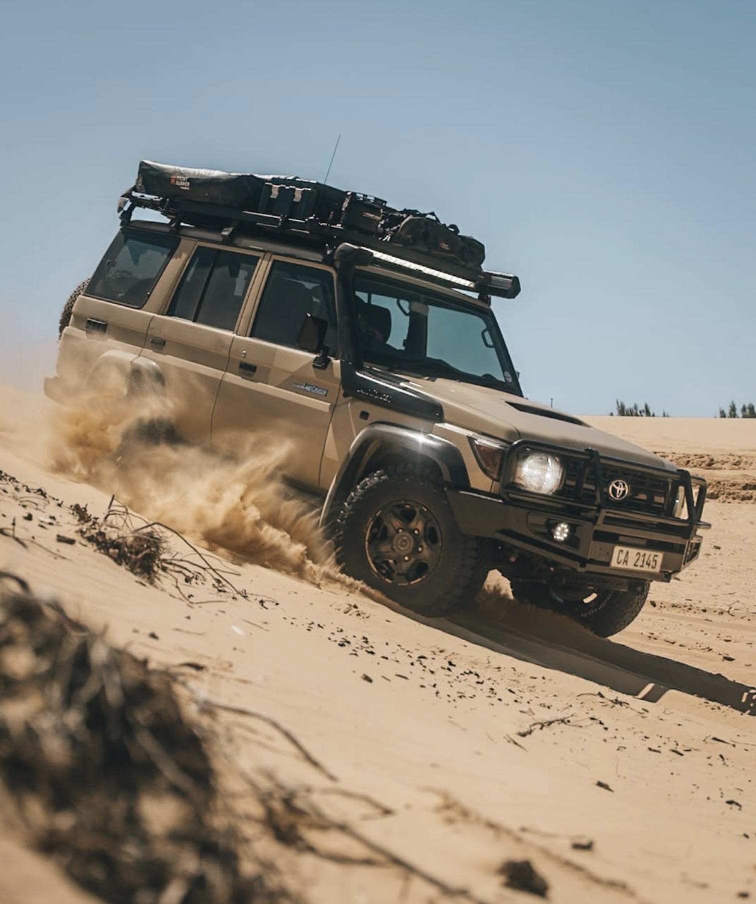 Land Cruiser 76 cresting a dune in soft sand — tyre pressure is everything