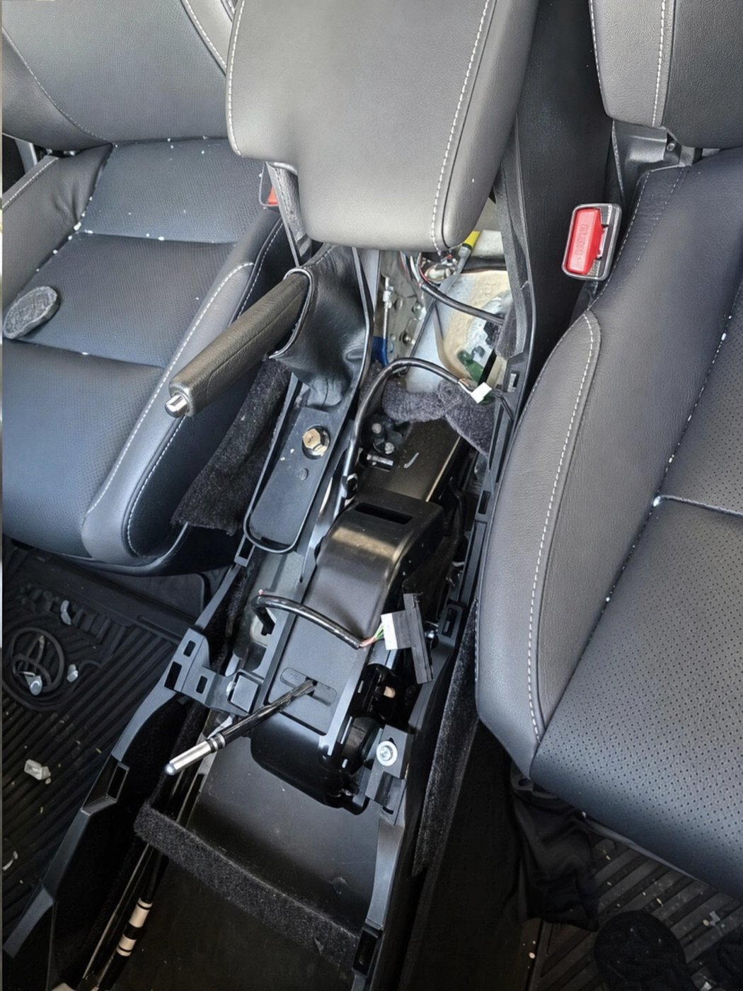A Titan Secure system being fitted to a Toyota, with the centre console lifted to reach the wiring
