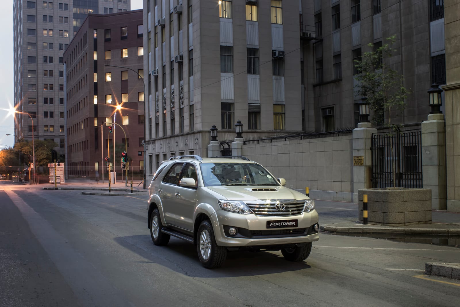 A champagne first-generation Toyota Fortuner on a city street at dusk.