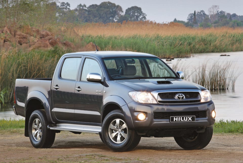 A grey seventh-generation Toyota Hilux D-4D double cab parked next to a river.