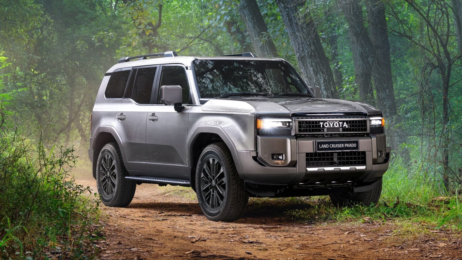 A new Toyota Land Cruiser Prado 250 on a dirt track through a forest.